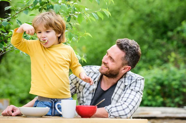 Healthy food and dieting. Childrens day. happy fathers day. Little boy with dad eat cereal. summer Morning breakfast. father and son eating outdoor. family dinner time. Enjoying every moment together — Stock Photo, Image