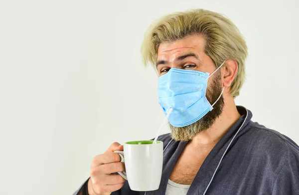 Een gemaskerde man drinkt thee met stro. Serieus over hygiëne. Bedek mond en neus met masker en zorg ervoor dat er geen gaten tussen gezicht en masker. Helemaal beschermd. Draag masker te beschermen tegen coronavirus — Stockfoto