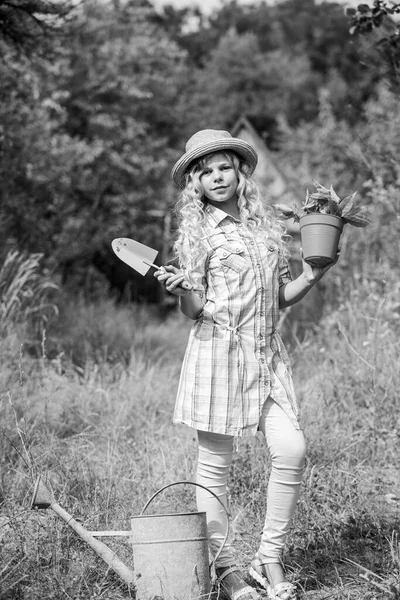 Child in hat with shoulder blade small shovel hoe. Happy smiling gardener girl. Ranch girl. Happy childhood. Planting plants. Little kid hold flower pot. Spring country works. Happy childrens day — Stock Photo, Image