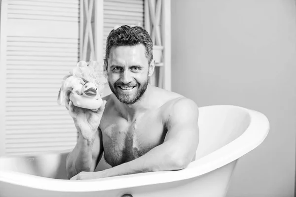 Macho profiter du bain. Homme sexy dans la salle de bain. Concept de sexe et relaxation. homme laver le corps musculaire avec mousse éponge. Laver soigneusement la mousse avec de l'eau. Macho nue dans la baignoire. drôle de canard. humeur ludique — Photo