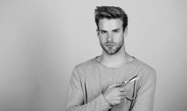 Sakallı adam. Elinde kuaför makası olan yakışıklı bir adam. Saç stili. Berberin kendi kendine bakması. Berber işi. Saç bakım ekipmanları. Erkek bakımı. Sakal stili. Berber dükkanı konsepti. Boşluğu kopyala