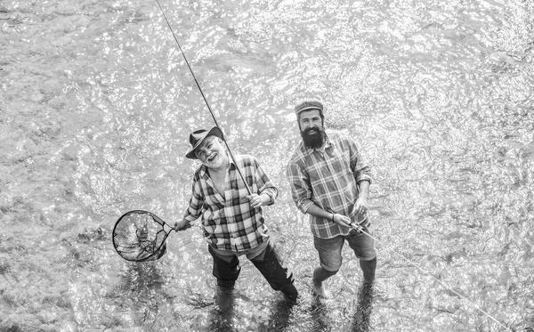 Collaboration. two happy fisherman with fishing rod and net. father and son fishing. Poaching. Camping on the shore of lake. Big game fishing. friendship. concept of rural getaway. hobby. wild nature — Stock Photo, Image