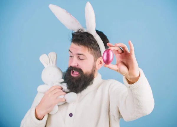 Kijk eens naar dat ei. Baard man met konijnenspeelgoed en paaseieren. Paashaas levert gekleurde eieren. Viering van de voorjaarsvakantie. Hipster met lange konijnenoren met ei leggende haas — Stockfoto