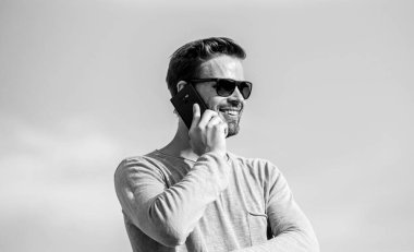 Davaları telefonla çözmek. Sıradan bir adam. Moda modeli. Seksi erkek gökyüzü arka planı. Maço adam cep telefonu kullanıyor. Hayattaki modern teknoloji. Her zaman görüşüyoruz. Kendine güvenen bir adam telefonda konuşur. Arkadaşına seslen