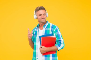 Ses kursları. İngilizce öğreniyorum. Modern teknoloji. Ses kitabı konsepti. Dünya çapında bilgi erişimi. Ses kütüphanesi. Yakışıklı öğrenci kulaklık takıyor ve kitap tutuyor. Dil çalış. Boş kurslar