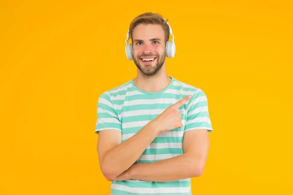 Продукт для виробництва музики. Щасливий чоловік вказує палець жовтим фоном. Просування продукту. Реклама товарів. Звукові технології. Музичний технічний продукт, який надихне вашу творчість, копіювати простір — стокове фото