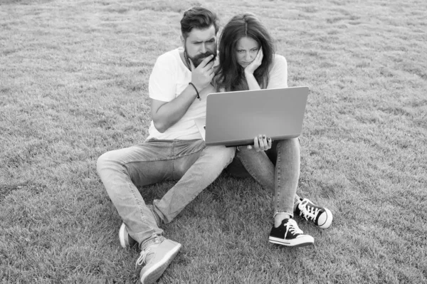 Subscribe online streaming services. Modern technologies. Couple sit lawn with notebook. Surfing internet. Spend leisure computer. Man girl looking screen. Online life. Online entertainment platform