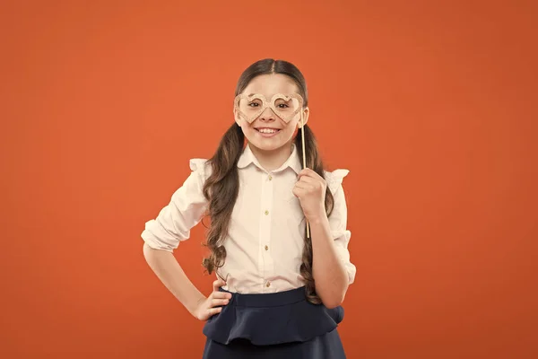 Βαλεντίνου. Το σύμβολο της καρδιάς της αγάπης. Μικρή έξυπνη μαθήτρια σε πορτοκαλί φόντο. Μικρό παιδί που φοράει γυαλιά ματιών έξυπνο στυλ. Ιδέα του σχολικού Κόμματος. Παιδί έξυπνη ματιά μέσα φωτογραφία περίπτερο στηρίγματα γυαλιά — Φωτογραφία Αρχείου