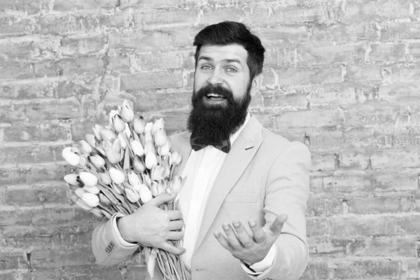 Romantic gift. Macho getting ready romantic date. Tulips for sweetheart. Man well groomed tuxedo bow tie hold flowers bouquet. How to be gentleman. Guide for modern man. Romantic man with flowers