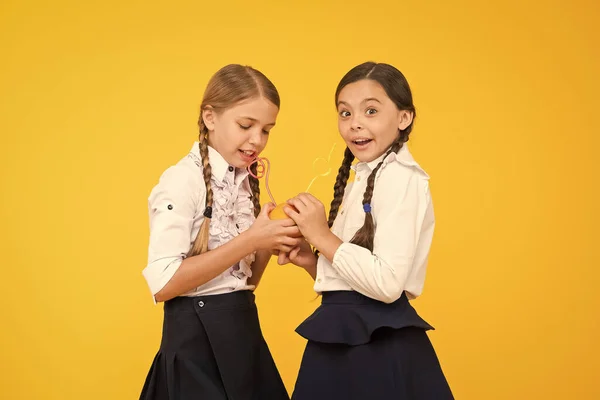 Vitamine C is cruciaal voor de groei. Kleine meisjes drinken vitamine sap van sinaasappel vruchten op gele achtergrond. Kleine schoolkinderen met gezonde vitamine drank. Voordelen van vitamine voedsel — Stockfoto