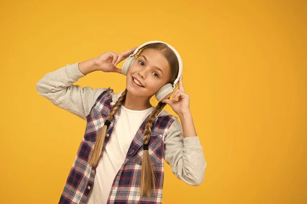 Menina feliz usando fones de ouvido modernos. Miúdo giro a desfrutar de som estéreo. Sem fios significa liberdade. Auscultadores com tecnologia sem fios. Criança pequena ouvindo música fones de ouvido sem fio modernos — Fotografia de Stock