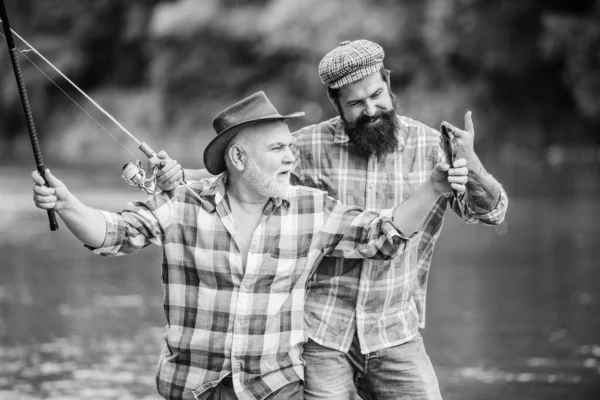 Pesca attività pacifica. Padre e figlio pescano. Nonno e amici maturi. Famiglia di pescatori. Asta da placcaggio. Attrezzature da pesca. Hobby sport. Pesca con mulinello. Soleggiato giorno d'estate al fiume — Foto Stock