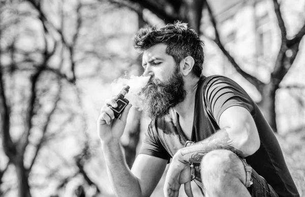 Hombre fumando cigarrillo electrónico. Hipster maduro con barba. hipster hombre mantenga el dispositivo de vapeo. Un brutal macho barbudo fumando cigarrillo electrónico. Seguridad y adicción a la salud. inhalando vapor. Resistente y varonil —  Fotos de Stock