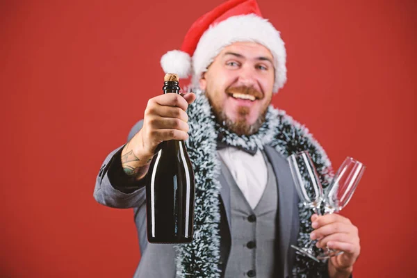 A szakállas, vidám hipszter télapó tartja az üveget. Ünnepeljük a karácsonyt. Vállalati karácsonyi buli. Igyunk pezsgőt. Főnök Mikulás kalap tinsel ünneplik újév vagy karácsony. Karácsonyi parti meghívó — Stock Fotó