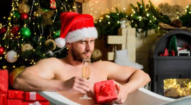 Spa ve sağlık. Sıcak banyo. Sıcak banyo sağlık yararları. Noel Baba sıcak banyoda lüks içinde. Keyfini çıkar. Kendimi şımartıyorum. Kış tatili Noel konsepti. Küvette yatan adam hediye kutusuyla rahatlar.