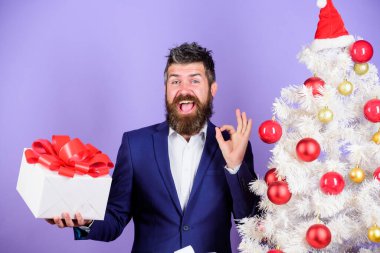 Gizli Noel Baba konsepti. Kış tatili Noel selamları. Meslektaşlarım için en iyi hediyeler. Ofis noel partisi. Adam sakallı hippi resmi takımı Noel ağacının yanında. Noel hediyeleri ve dekorasyonlar