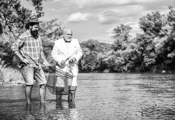 Squadra di pesca. Giornata attiva. Giornata di famiglia. Hobby e tempo libero. Pace della mente e tranquillità. Pesce d'acqua dolce. Uomo barbuto e brutale pesca hipster. Prendere il pesce con anima gemella. Amici cattura del pesce — Foto Stock