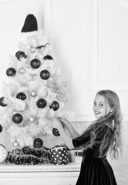 Dziecko umieścić christmas ornament piłka na sztuczne biały drzewo. Najlepsze świąteczne dekorowanie pomysły dla dzieci pokój. Dzieci można rozjaśnić choinki, tworząc własne ozdoby. Dziewczyna z okazji świąt — Zdjęcie stockowe