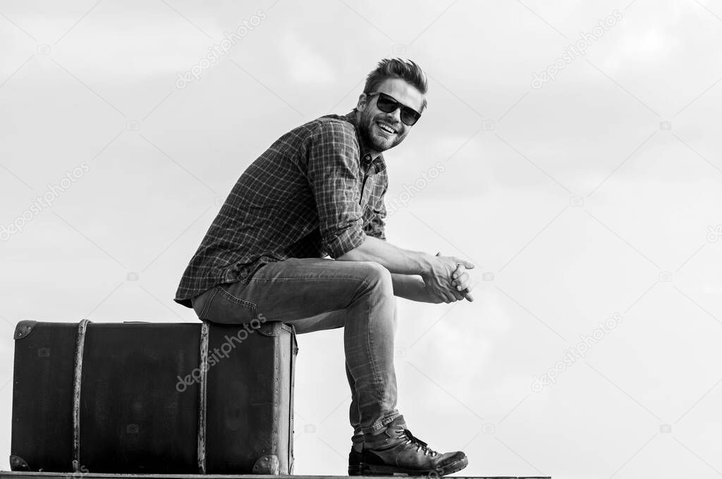Travel agency. Travel with luggage. Travel blogger. Vacation time. Man sit on suitcase before journey. Business trip. Handsome guy traveler. Guy outdoors with vintage suitcase. Luggage concept