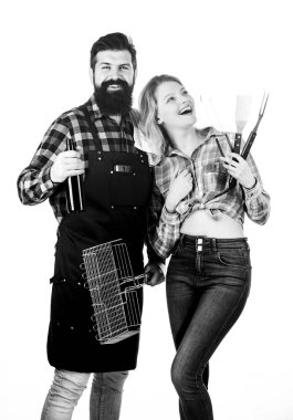 Sakallı hippi ve kız barbekü partisi için hazır. Kızartma ve ızgara yemek. Birlikte yemek pişirmek. Birbirine aşık çiftler yemek pişirme aletlerini barbekü olarak tutarlar. Açık havada et kızartmak için aletler. Piknik ve barbekü