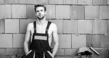 Yakışıklı adam tulum giyer. Dinlen biraz. Seksi işçi seni. Çekici bir işçi. İnşaat. İşçi tuğlası duvar arka planı. Temel görevleri yerine getir. Erkeklik kavramı. Genel bakım tamircisi