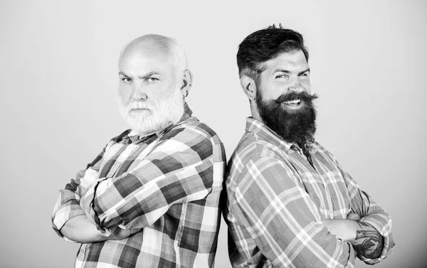 Brutal guys with long beard. Father and son. Hairdresser salon. Barbershop concept. Men bearded hipster stand back to back. Bearded friends. Family team. Barber well groomed handsome bearded man