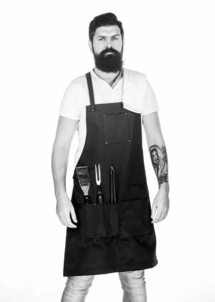 Baard hipster dragen schort voor barbecue. Roosteren en grillen van voedsel. Tips koken vlees. Gereedschap voor het roosteren van vlees buiten. Picknick en barbecue. Hoe kies je vlees voor biefstuk. Professionele barbecue gebruiksvoorwerp — Stockfoto