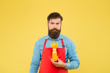 Taze vitamin dağıtıyorum. Hipster içeceği. Erkek sakallı şef organik domates ve şişe sarısı arka plana sahiptir. Vejetaryen beslenmesi. Meyve suyu. Taze meyve suyu. Sıkarak smoothie