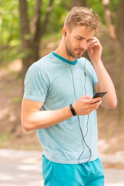 Fitness müziği. Atletik adam akıllı telefondan müzik dinler. Mobil müzik. Güçlü bir kardiyo çalışması için müzik karışımı ideal. Spor ve aktif yaşam tarzı. Sağlık ve sağlık. Açık havada eğitim.