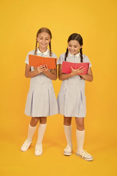 おとぎ話で迷子になった学校に戻る小さな女の子は、ワークブックとメモ帳を保持します。子供のための百科事典の本。小さな女の子は文学が大好きです。古い学校。レトロな制服を着た幸せな友達。ヴィンテージ子供のファッション — ストック写真