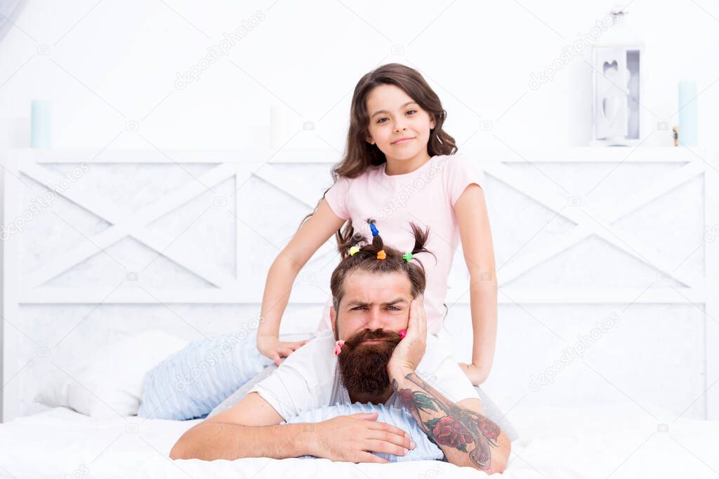 Dad who trapped at home with coronavirus quarantine and kid. Family leisure. Pajamas party. Happy childhood. Relaxing in bedroom. Girl making hairdo for dad. Quarantine with children. Happy family