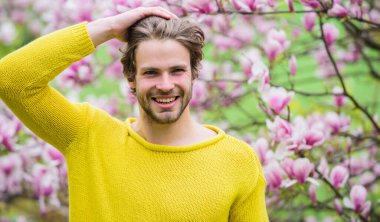 Hippi çiçek aromasının tadını çıkarır. İlkbahar konsepti. Tıraşsız bir adam manolya çiçeği koklar. Erkek çiçekli arka plan çözüldü. Bahar güzeli. Bahar sezonu. Botanik ve doğa. Mutlu bahar konsepti