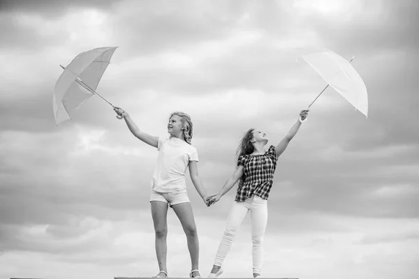 Niños despreocupados al aire libre. Libertad y frescura. Pronóstico del tiempo. Cambio de clima. Chicas amigas con sombrillas de fondo cielo nublado. Listo para cualquier clima. Viento o lluvioso estamos preparados — Foto de Stock