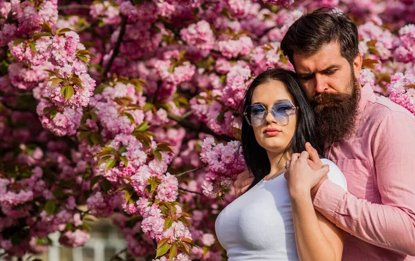 Travel together. Ideas for spring vacation. Couple relaxing in garden. Spring inspiration. Our place of power. Positive vibes. Fashion people. Spring collection. Bearded hipster hug pretty girl — Stock Photo, Image