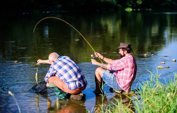 Vliegvissen hobby van mannen. pensioenvisserij. Gelukkige vissers vriendschap. gepensioneerde vader en volwassen zoon met baard. groot wild vissen. ontspannen op de natuur. Twee mannelijke vrienden die samen vissen. Het is een grote vis. — Stockfoto