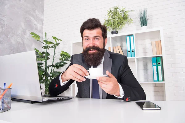 Discuta los negocios con café. Un jefe guapo se sienta en la oficina bebiendo café. Cómodo espacio de trabajo. Traje formal de hombre de negocios barbudo relajándose con café. Rutinas de vida de oficina. Muy buen capuchino. — Foto de Stock
