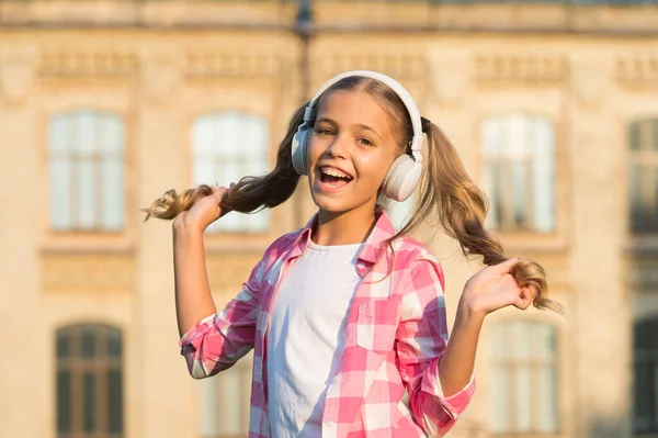 Inspired by favorite song. small girl listen to music. kid in headphones. childhood happiness. happy child in playful mood has blonde hair. cute and stylish hairstyle. leisure time in spring — Stock Photo, Image