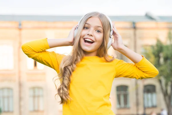 Musikkanal. Mädchen hören Musik modernes Gadget. Kind glücklich mit drahtlosem Headset im Freien Sonnenuntergang städtischen Hintergrund. Stereo Kopfhörer. Kind mit moderner Technologie. Musik für die Seele. Modernes Kind — Stockfoto