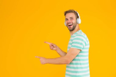 Kahramanca müzik dinlemek, daha pozitif hissetmek, aktif ve ilham verici. Adam kopyalama alanını işaret ediyor. Mükemmel bir fikir. Happy Man müzik kulaklığı dinler. Kablosuz kulaklıklar. Enstrümantal müzik