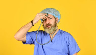 Steteskoplu cerrahi üniformalı bir adam. Sağlık sigortası. Ciddi doktor fonendoskop kullanır. Koronavirüs taşıyıcısı. Çin 'den gelen virüs enfeksiyonu. Test ve tedavi. sağlık ve sağlık kontrolü