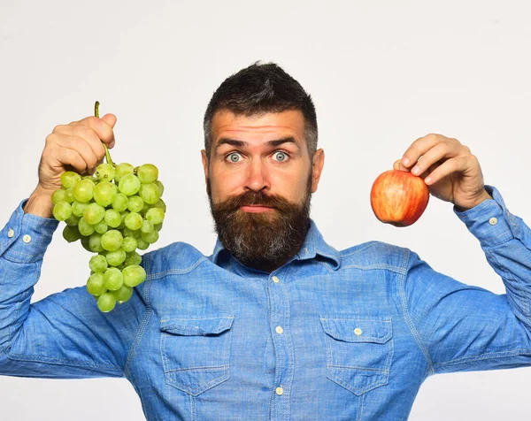 턱수염을 한 남자가 푸른 포도와 사과를 한 다발들고 있다 — 스톡 사진