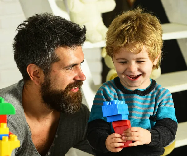 Otec a syn se šťastnými tvářemi vytvářejí barevné konstrukce — Stock fotografie