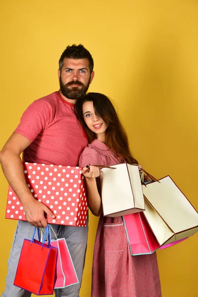 Pareja enamorada sostiene bolsas de compras sobre fondo amarillo. —  Fotos de Stock