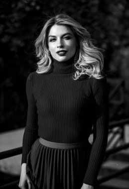 Kadınlık ve şefkat. Sonbahar tarzı kıyafetler. Sonbahar modası. Sonbahar parkında yürüyen bir kadın. Samimi örgü giysiler. Örgü süveter. Sevimli kız geçen güneş ışınlarının tadını çıkarıyor. Şık kıyafetler.