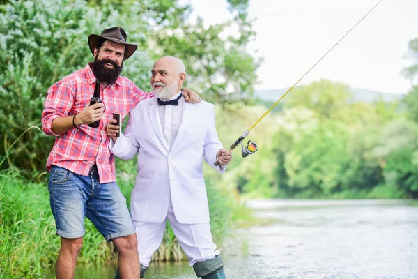 パーティーだ。趣味とスポーツ活動。釣竿を持った漁師が2人。引退した実業家。男性の友情。成熟した男魚屋は引退を祝う。夏の週末だ。父と息子の釣り — ストック写真