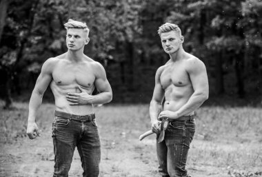 Eğitimden sonra dinleniyorum. Atletik adam balta kullanıyor. Çifte güç. Erkeklik ve vahşet kavramı. Seksi kaslı erkekler vahşi görünürler. Başarı sporu. Baltalı kaslı ikizler.