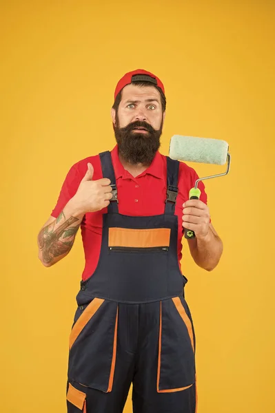 Male decorator in overall. sad bearded man worker with roller tool. hipster scene-painter yellow background. erector assistant in work uniform. engineer designer ready to paint wall. repair concept — 스톡 사진