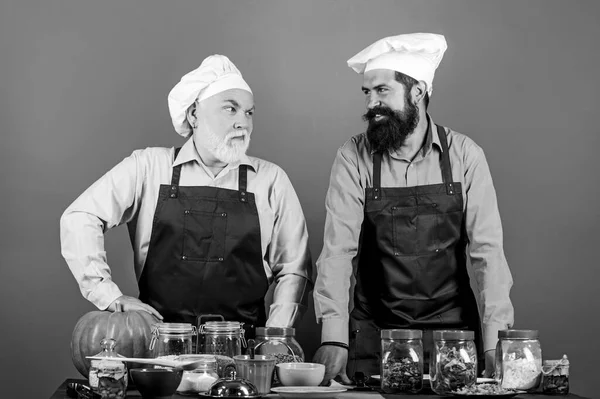 Family restaurant. Mature bearded men professional restaurant cooks. Chef men cooking. Prepare food. Culinary recipe. Culinary book. Selected ingredients. Homemade meal. Father and son culinary hobby