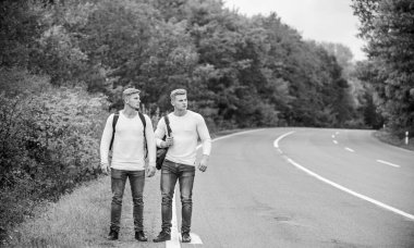 Gitmemiz gerek. Yolculuk tutkusu konsepti. Arkadaşlarla yürüyüş yapmak iyidir. Kendilerini bulmaya gittiler. Otostop çekerek. Yol boyunca yürüyen ikizler. Boş yolda otostop çekerek. Otostop yaparak. Yol gezisi