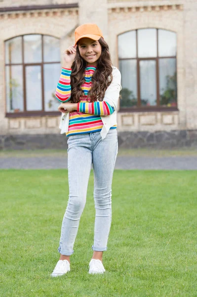 Teen in stile casual. concetto di parrucchiere. felicità infantile. ragazza felice con lunghi capelli ricci. grazioso bambino sorridente all'aperto. bellezza e moda del capretto. allegra ragazza della scuola indossare cappello — Foto Stock